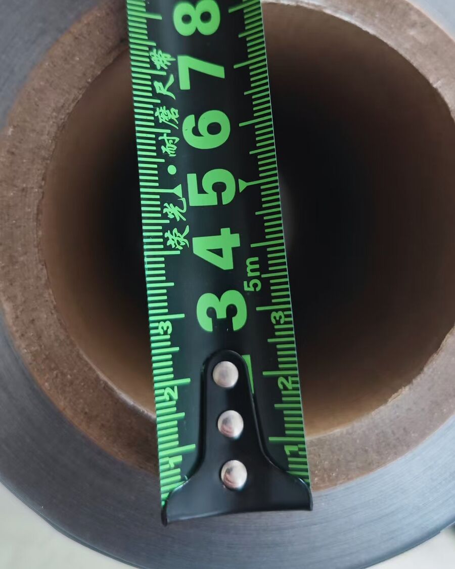 A tape measure held across the end of a rolled material